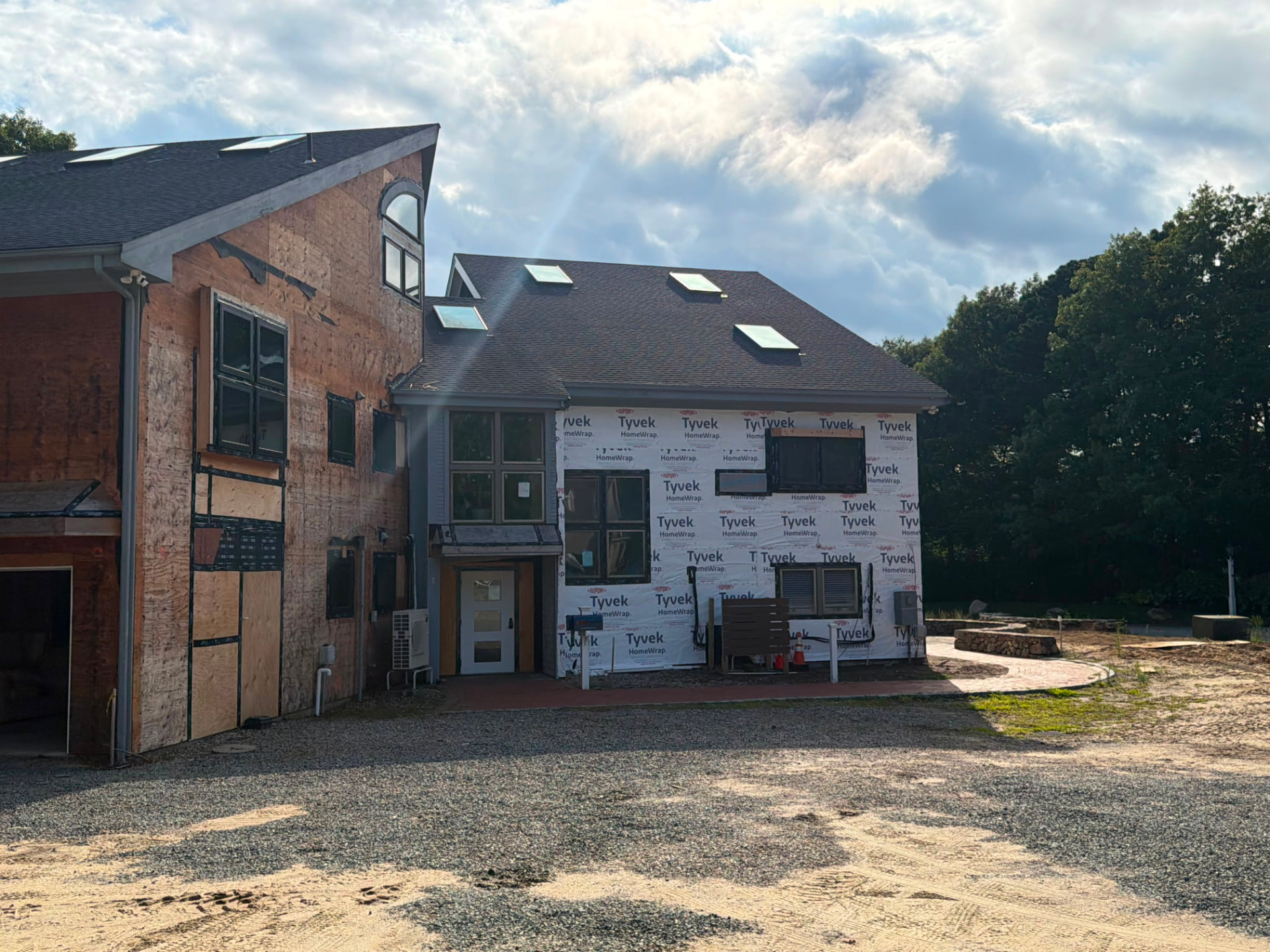 Rear elevation of a large home under renovation with new roof, skylights and house wrap