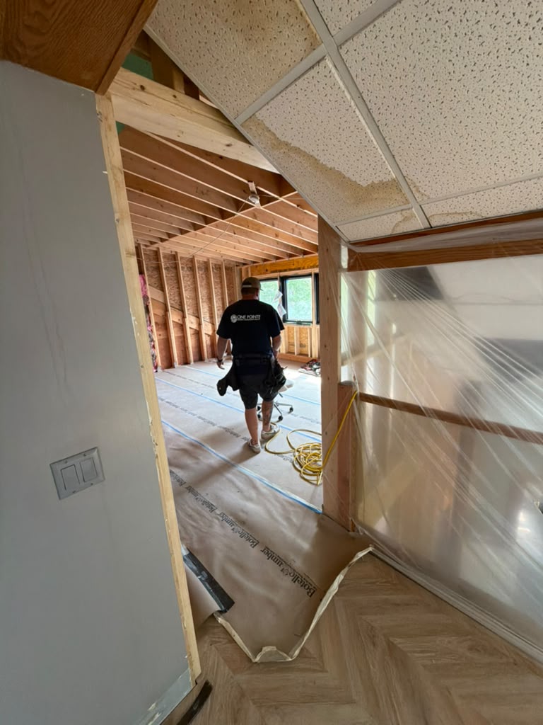 Interior wall removed down to studs with plastic dust containment and floor protection