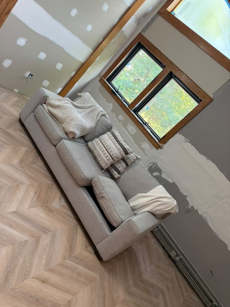 Interior room with freshly taped and skim coated drywall over new herringbone flooring