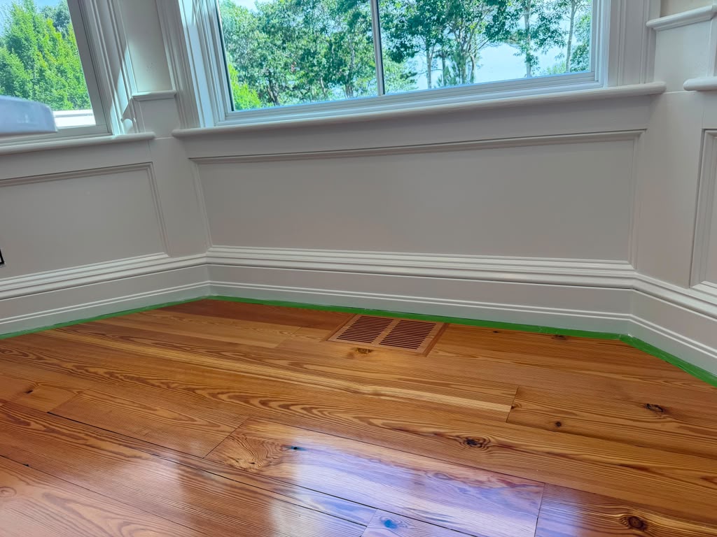 Finished white wainscoting and baseboard trim above refinished hardwood flooring